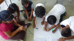 Kinder hocken über einem Fragebogen und suchen nach Unterschiede zwischen den Philippinen und Österreich